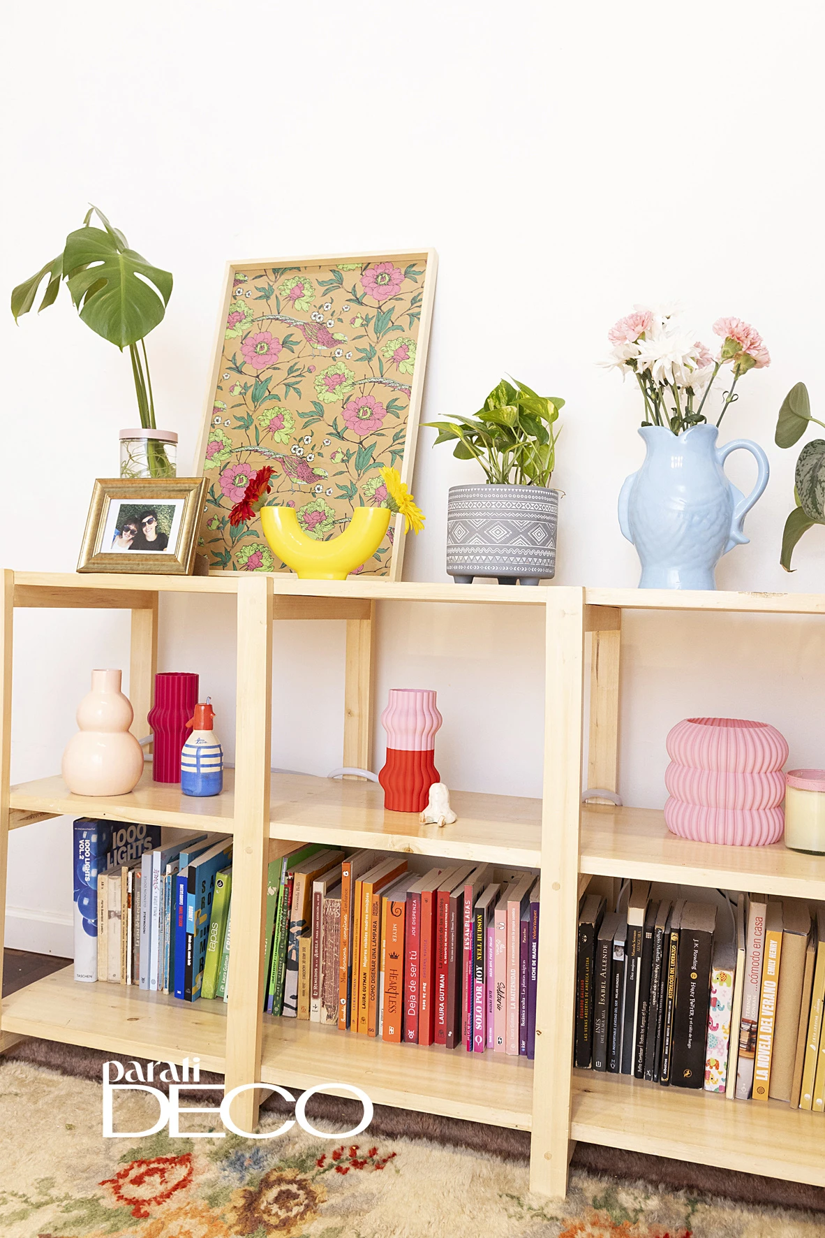 En la estantería del living, hay objetos decorativos -de colores vibrantes y amigables formas- y libros organizados por colores. 